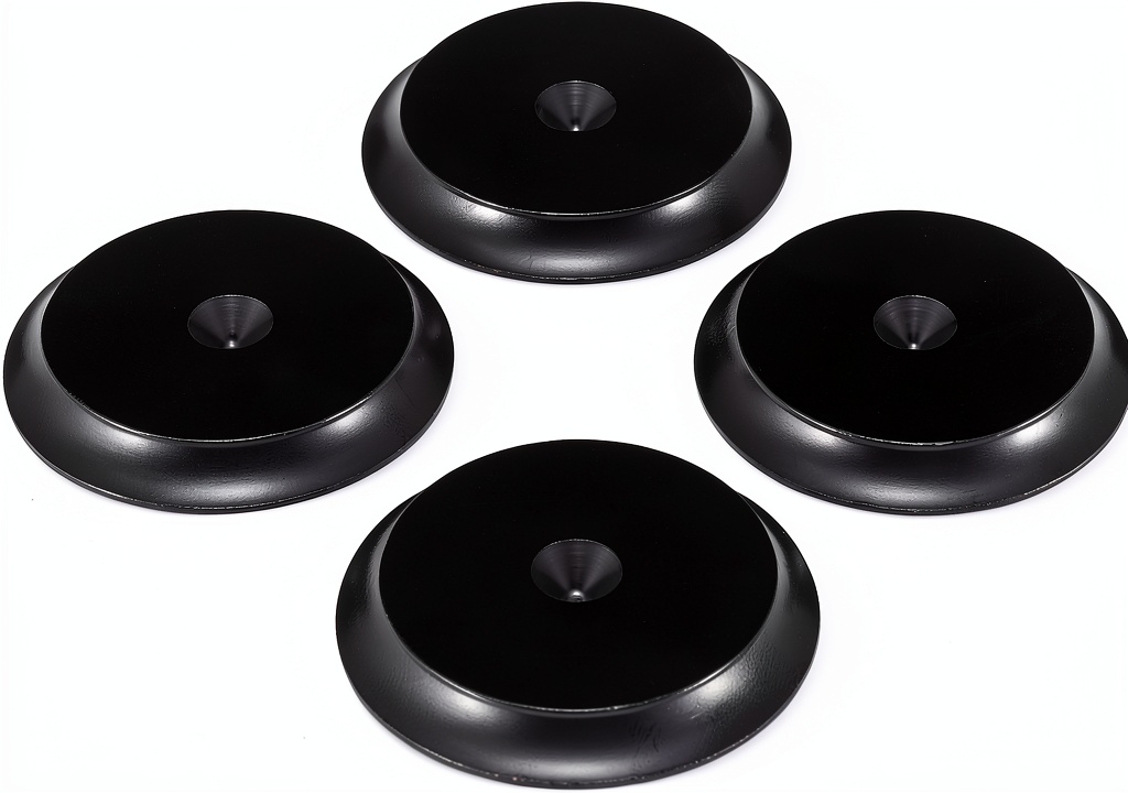 Speaker isolation discs placed under studio monitors on a wooden desk